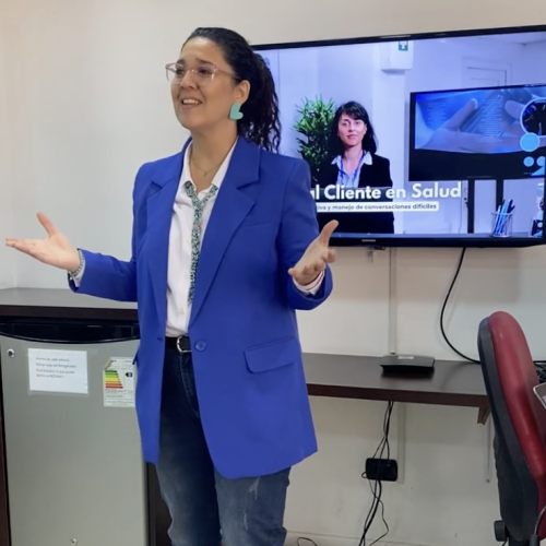 Psicóloga facilitando capacitación en comunicación asertiva en atención al cliente para empresa en Santiago de Chile.